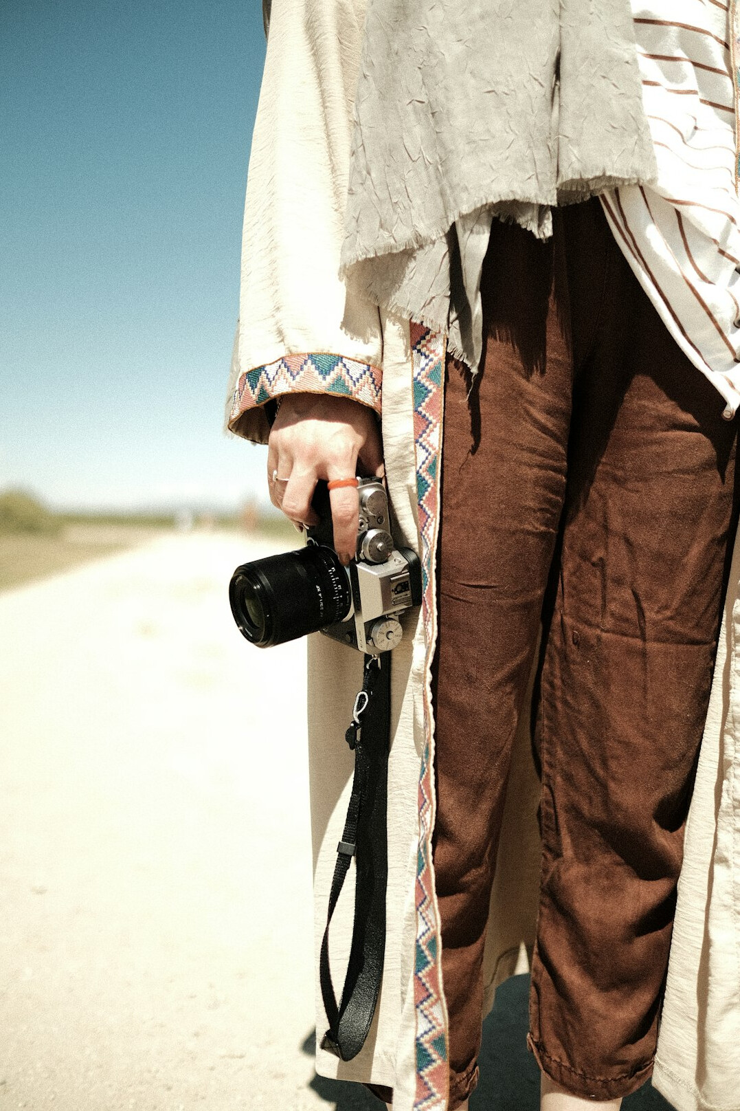 Portrait of an Indigenous Canadian woman photographer holding a vintage film camera against a warm neutral background