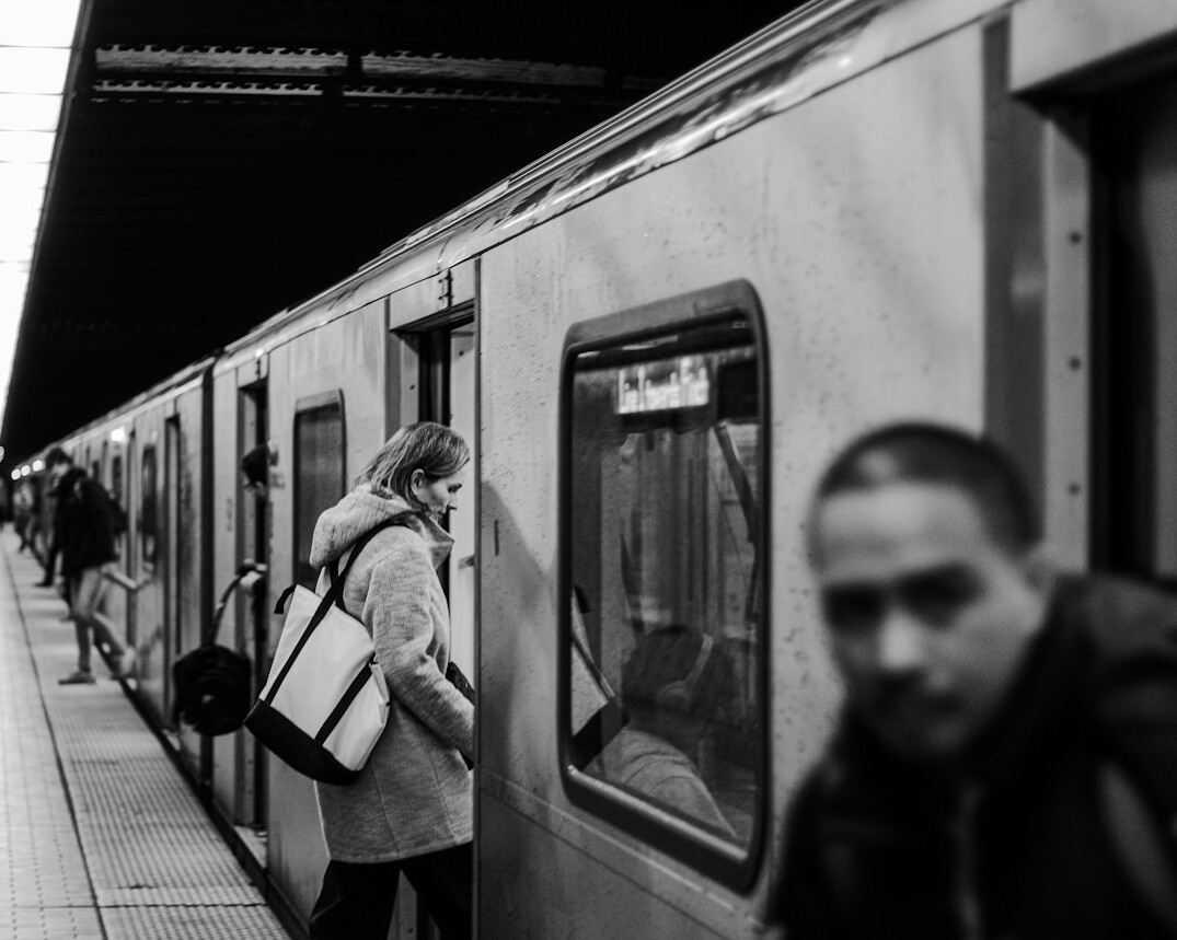 Commuters of diverse backgrounds waiting on a Toronto subway platform during rush hour